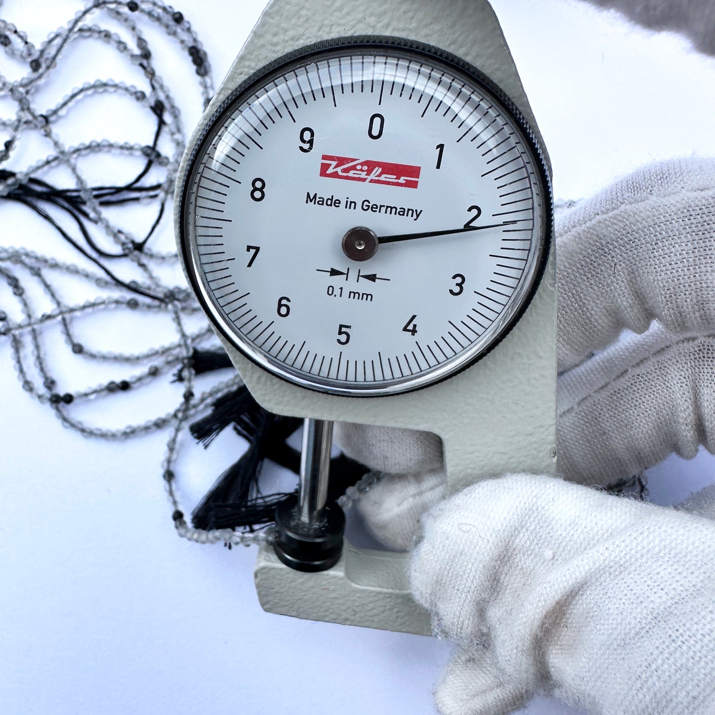 A dial gauge measures the black rutile faceted rondelle 2.1mm gemstone.