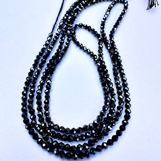 Coated Black Spinel faceted rondelle beads with glossy black sparkle arranged on a 33cm strand for jewellery making.