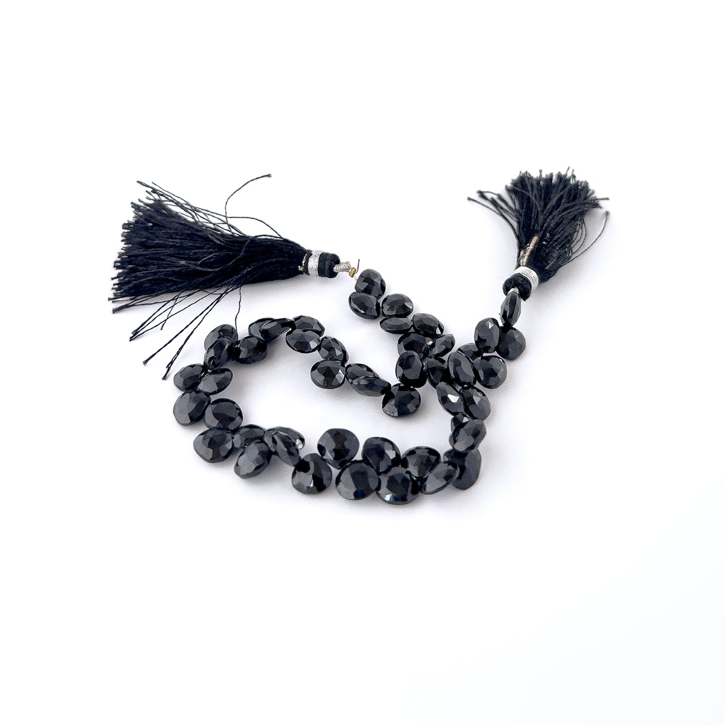 Black Spinel briolette beads featuring teardrop shaping and bright mirror‑like shine throughout a 21cm strand.