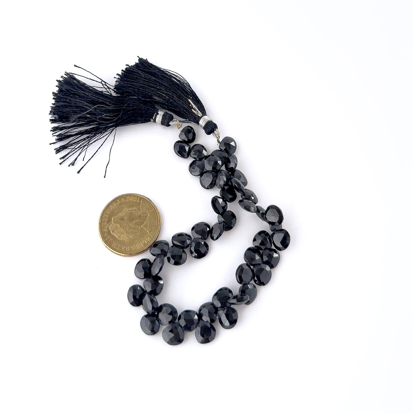 A coin is placed near Black Spinel briolette beads to show the 7.5–8mm size range.