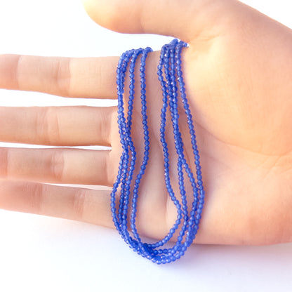 A person holds delicate strands of Blue Chalcedony beads, showcasing their faceted rondelle design.