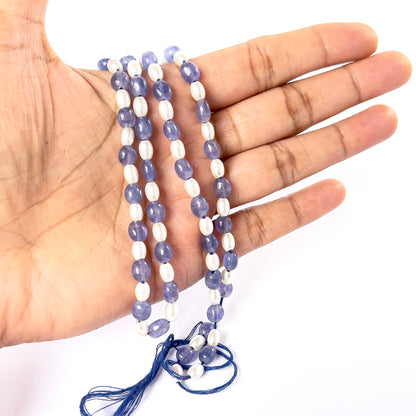 A person holds delicate strands of Blue Quartz and Shell Pearl smooth oval beads, showcasing their polished design.