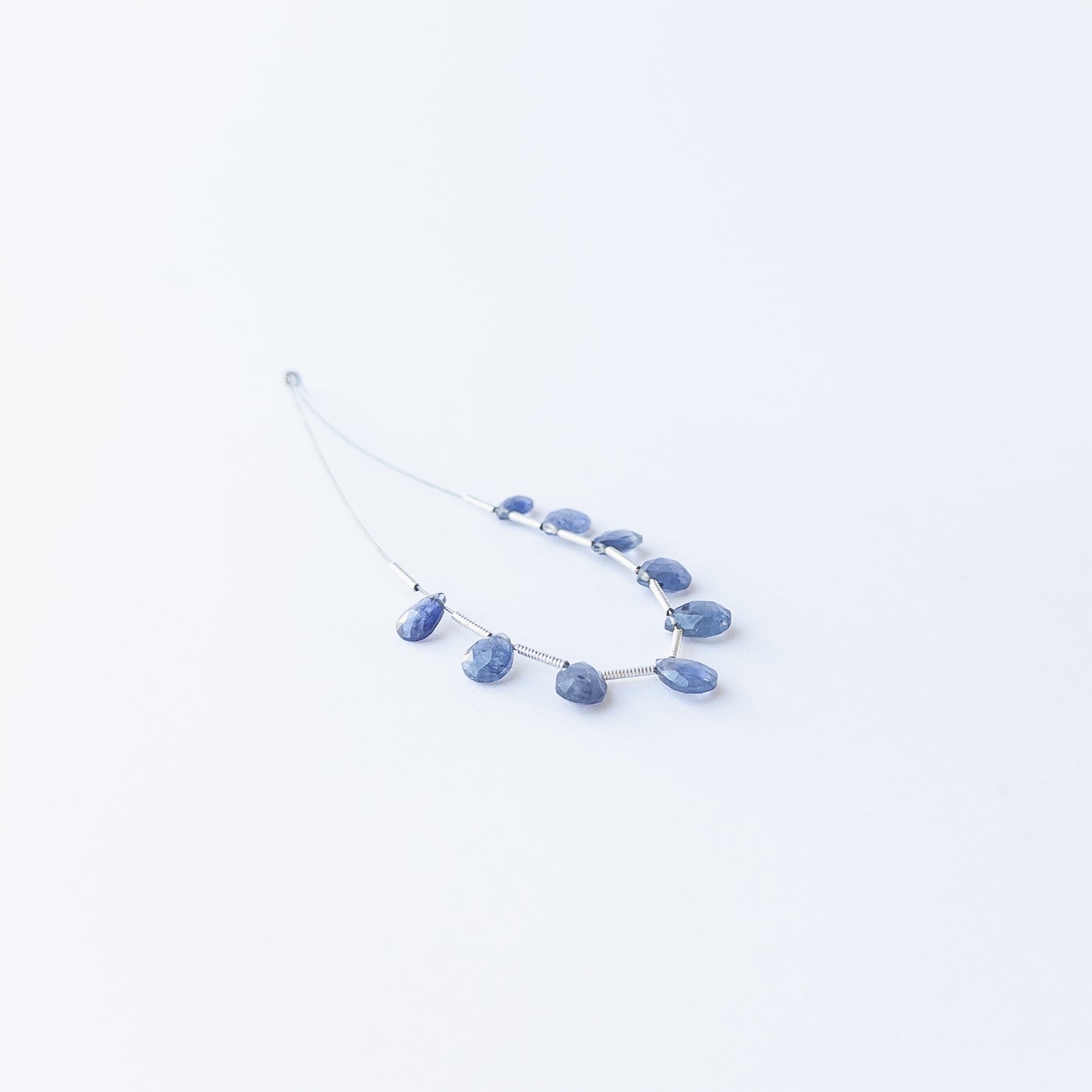 Handmade jewellery components featuring sparkling Blue Sapphire briolette beads in a neatly arranged set.