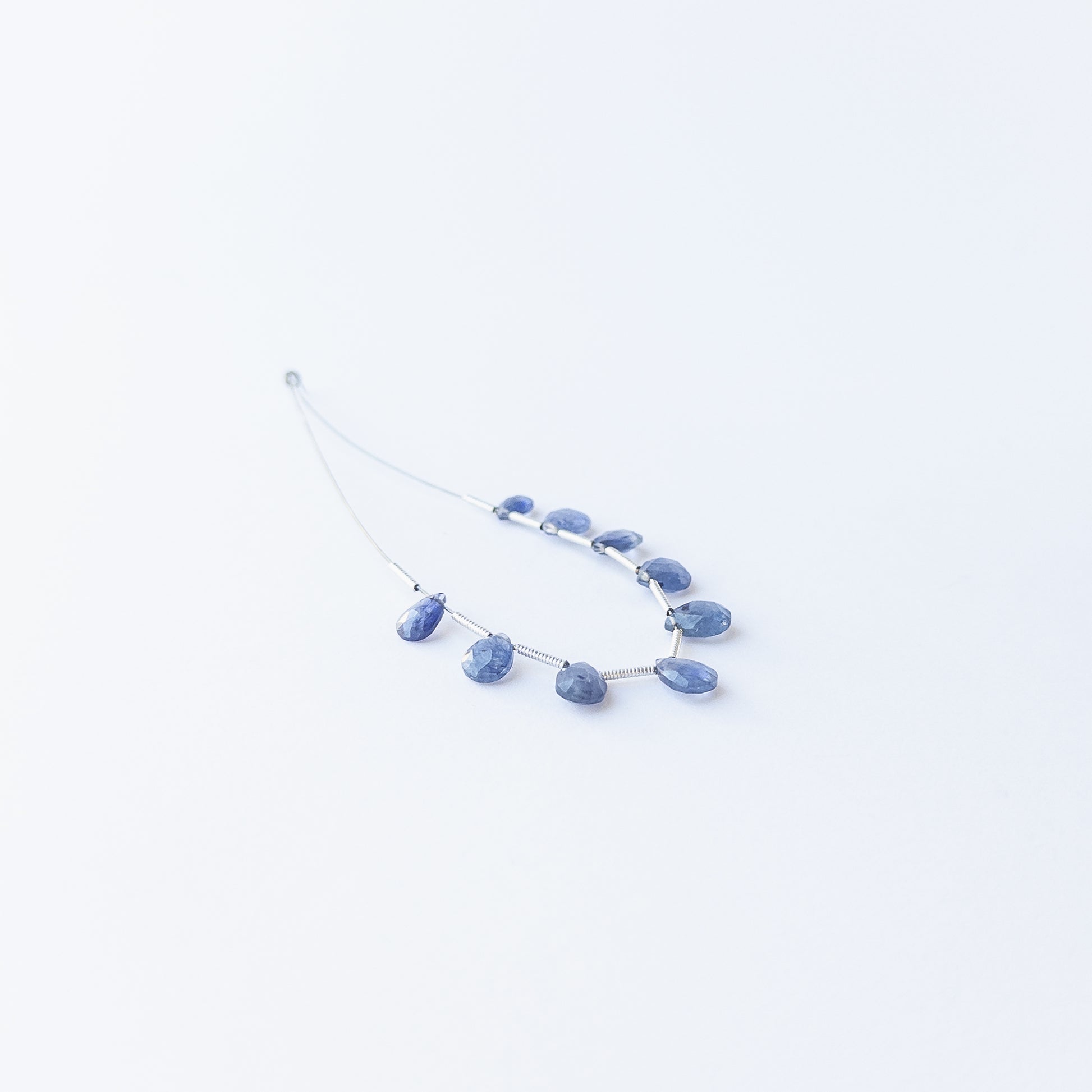 Handmade jewellery components featuring sparkling Blue Sapphire briolette beads in a neatly arranged set.