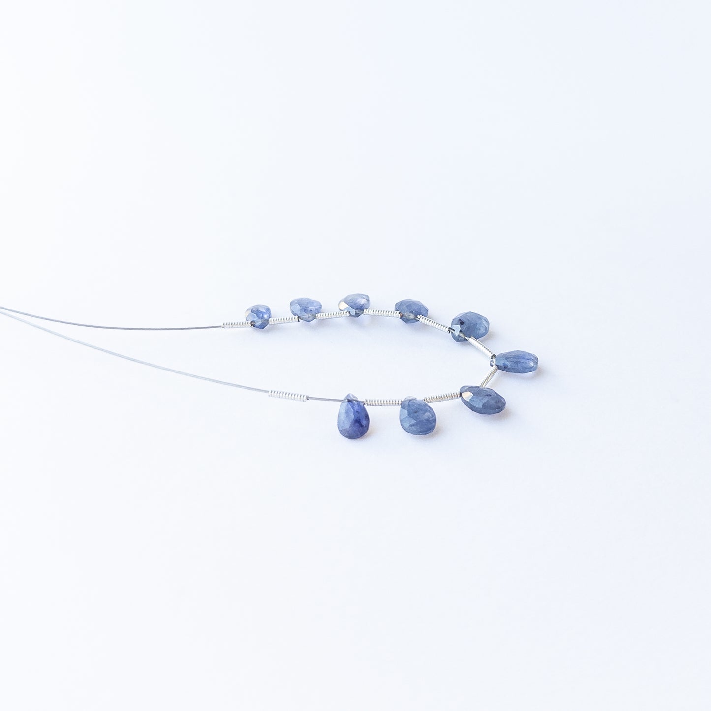 Blue Sapphire faceted briolette gemstone beads arranged in a deep blue strand for handmade jewellery making.