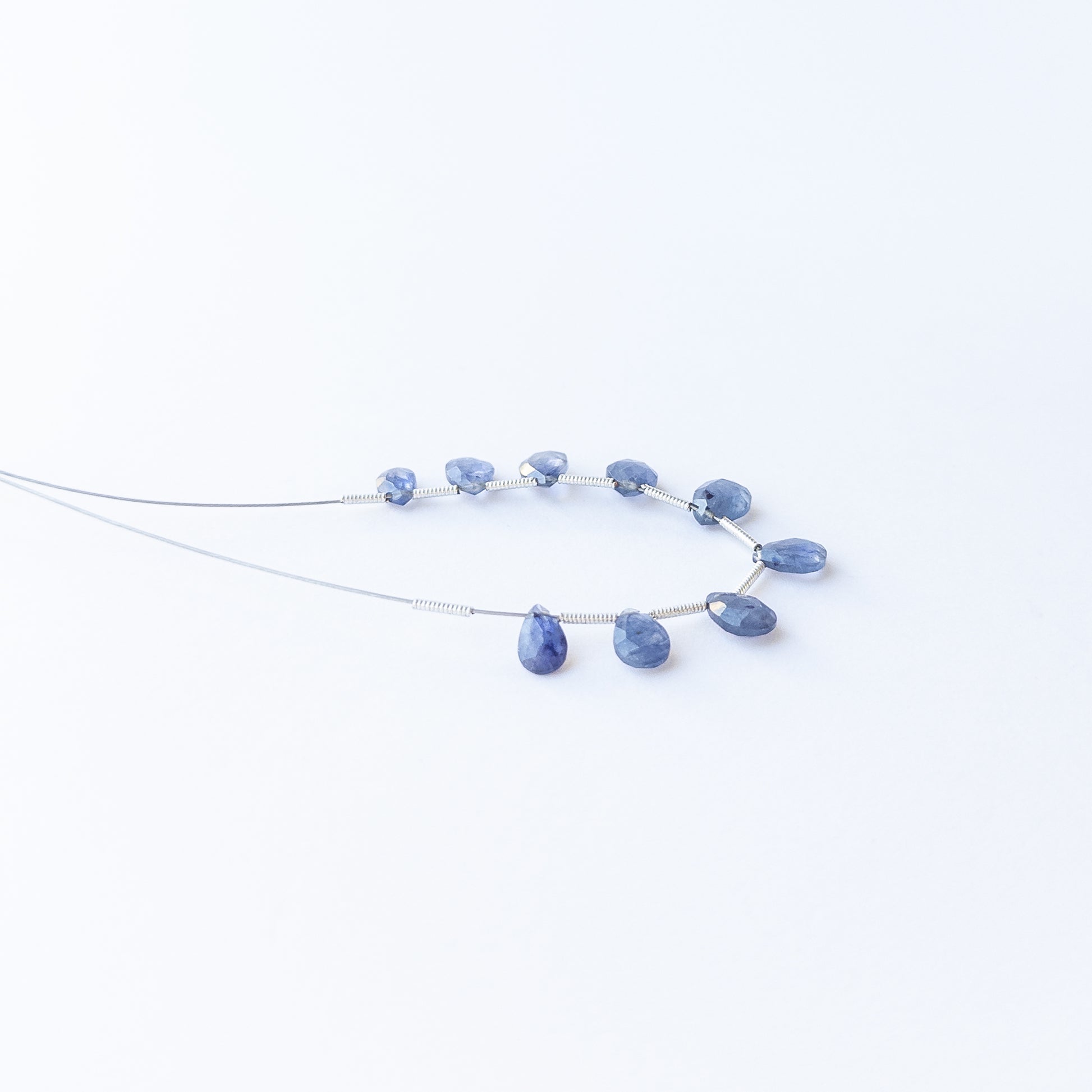 Blue Sapphire faceted briolette gemstone beads arranged in a deep blue strand for handmade jewellery making.
