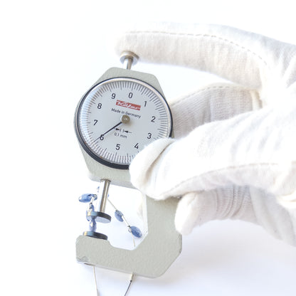 A dial gauge measures the Blue Sapphire faceted briolette 5.2–6.4mm gemstone.