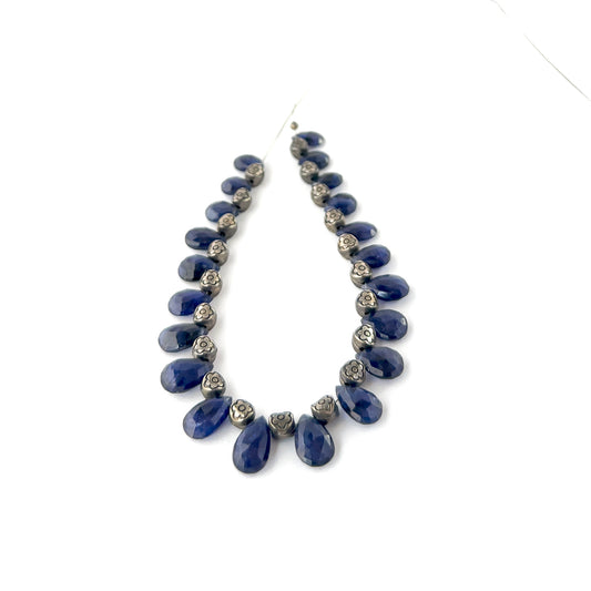 Blue Sapphire faceted briolette beads sized 6–7.5mm arranged as a 21‑piece set, showing deep midnight‑blue tones and sharp reflective sparkle across 94 carats.