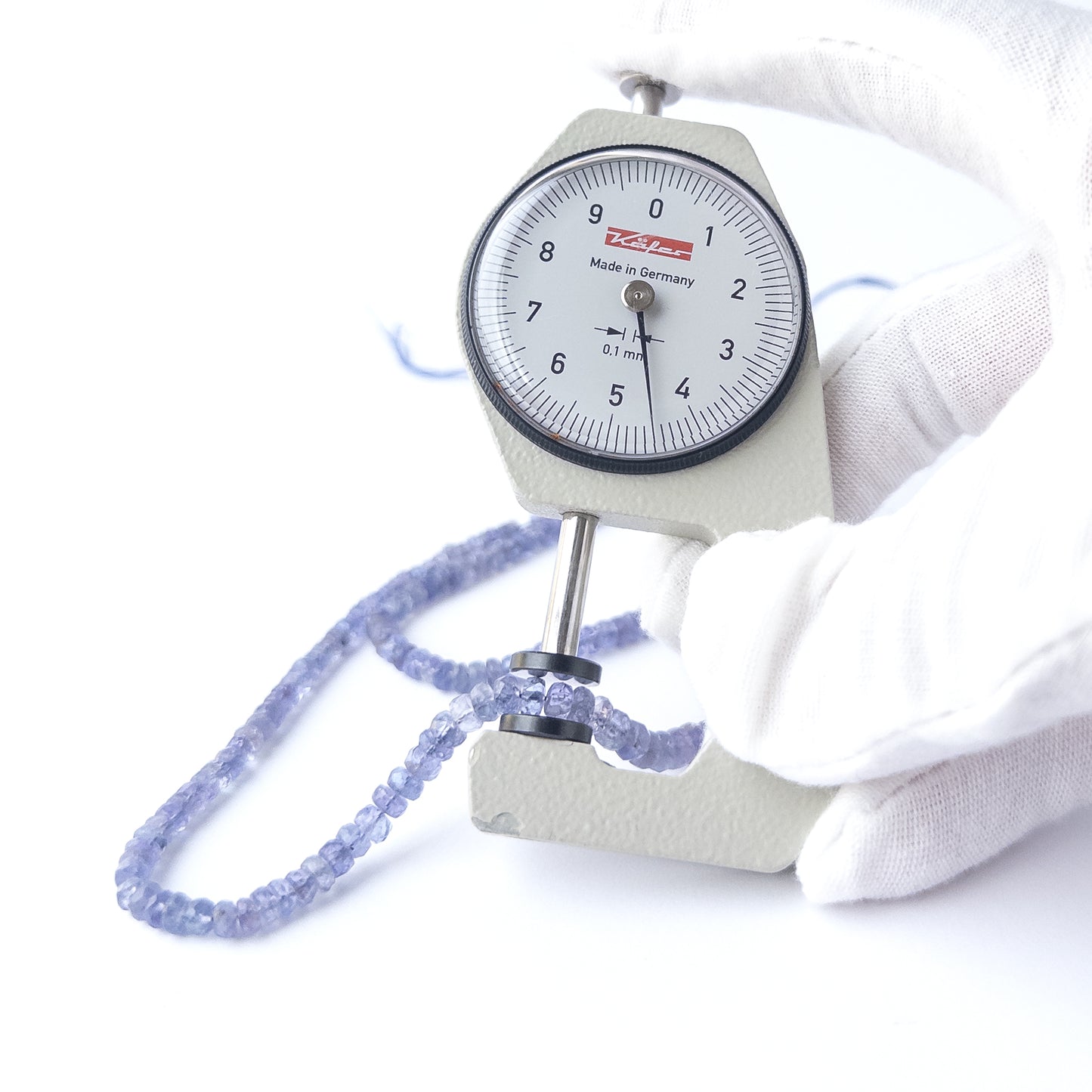 A dial gauge measures the Blue Sapphire faceted rondelle 3–4.2mm bead size gemstone.