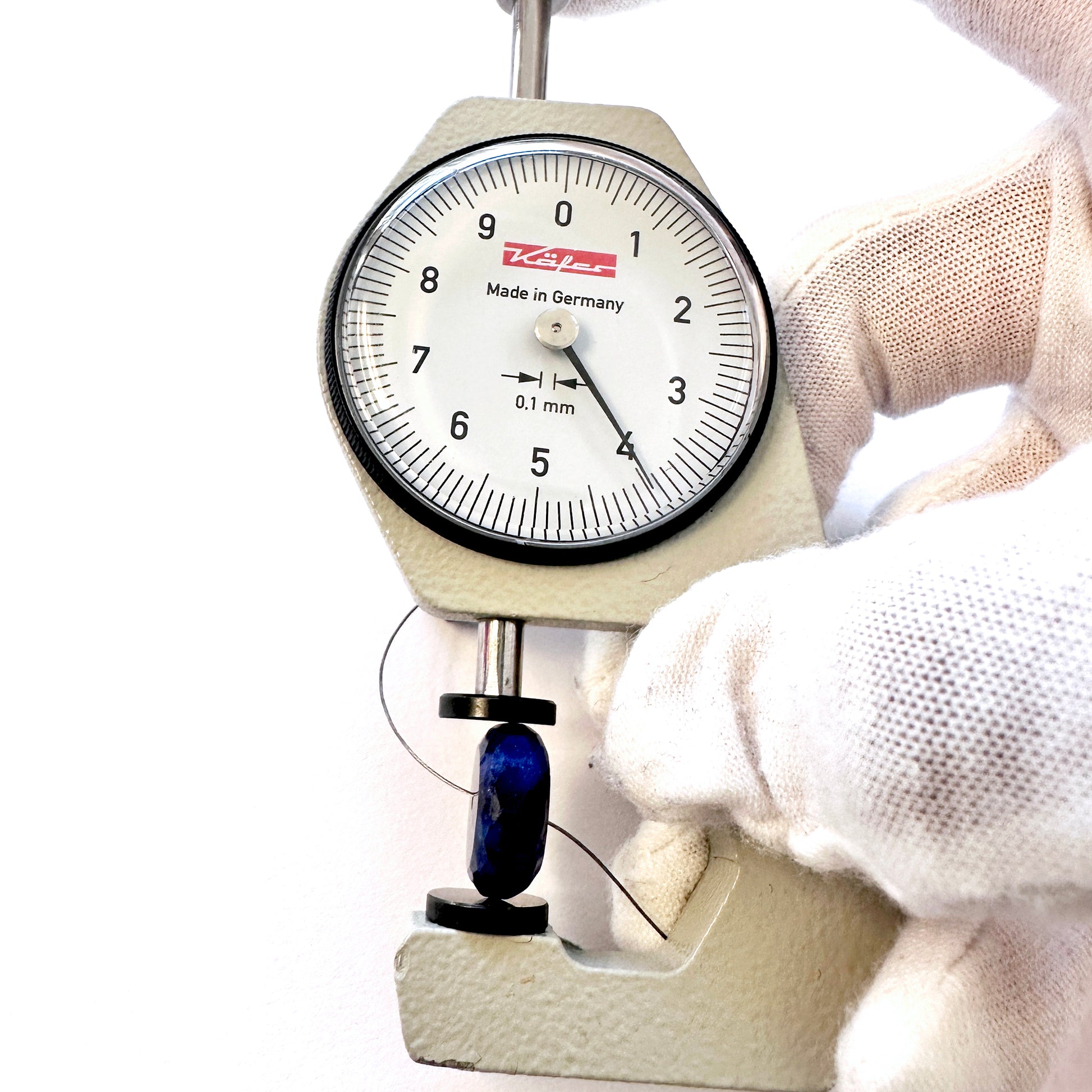 A dial gauge measures the Blue Sapphire Faceted Rondelle 14mm gemstone.