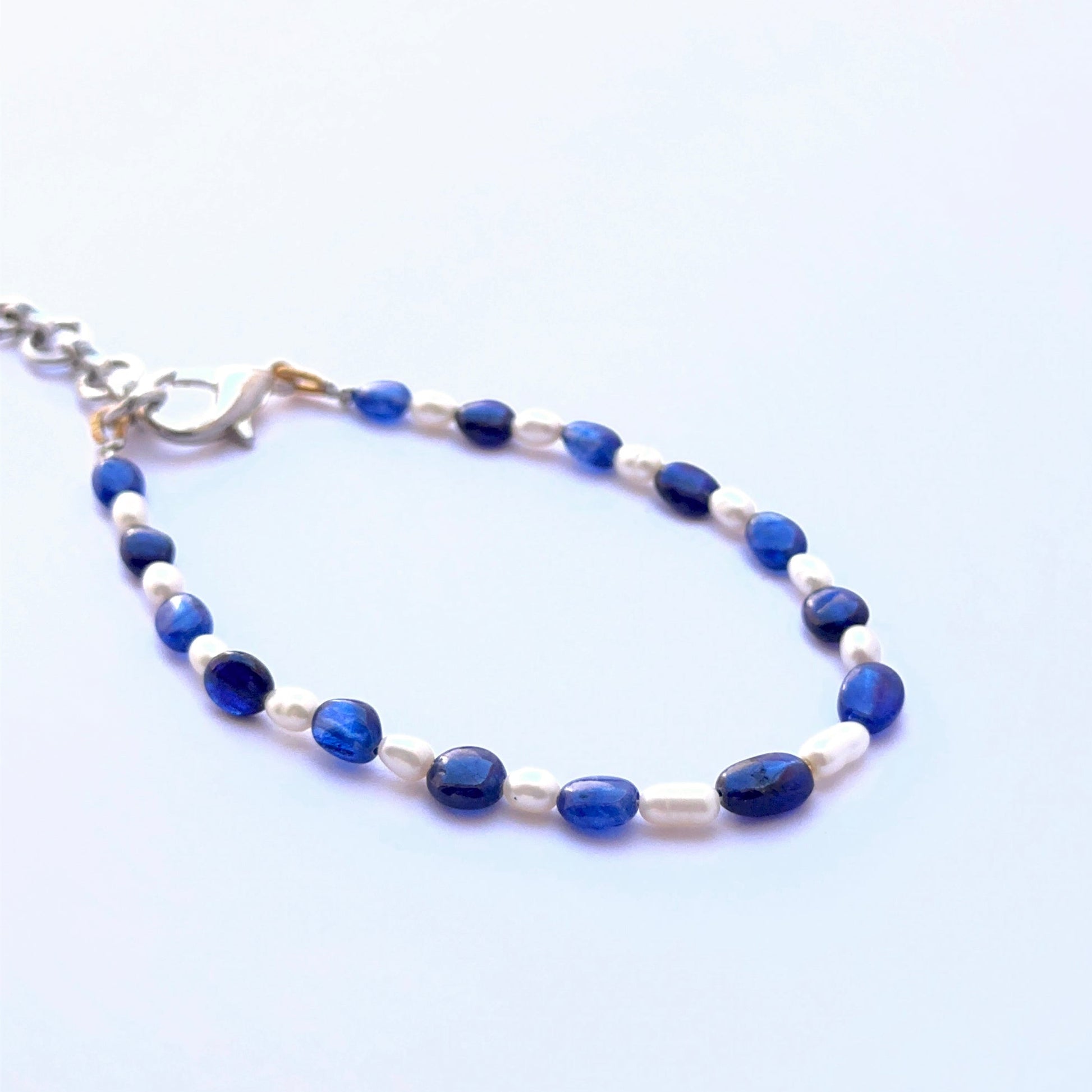 Close‑up of sapphire and pearl beads arranged on a polished bracelet.