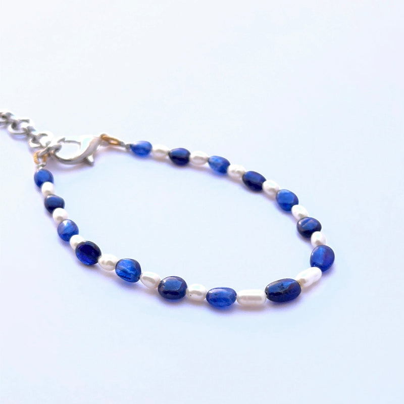 Close‑up of sapphire and pearl beads arranged on a polished bracelet.