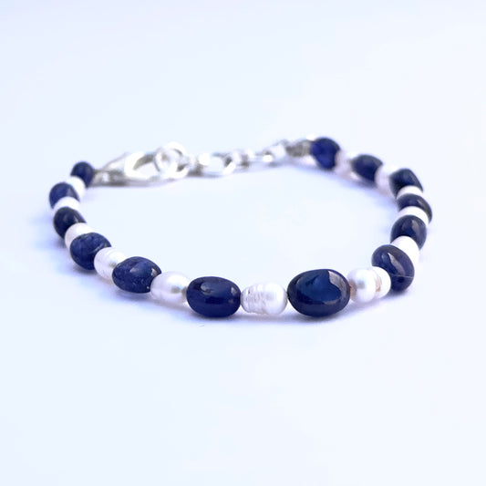 Close-up of polished sapphire and pearl stone beads arranged in a stylish bracelet.