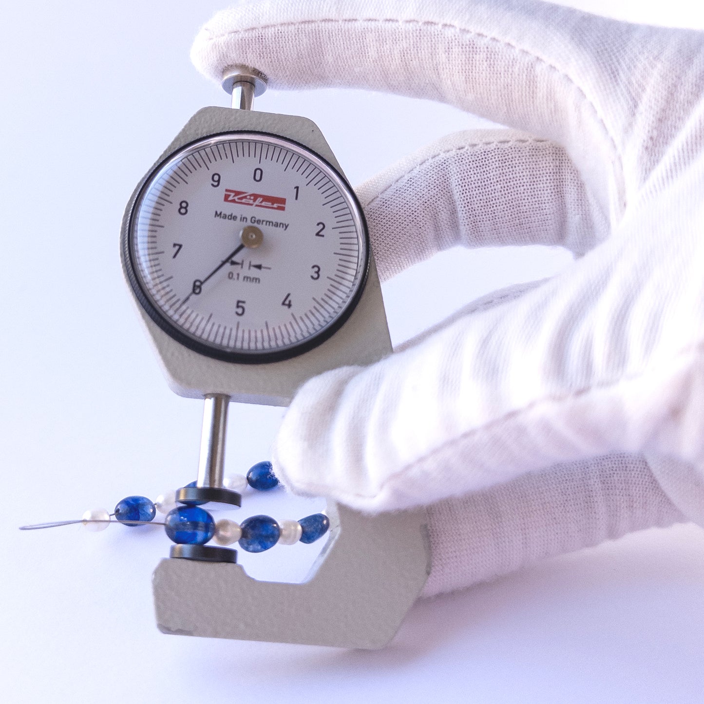 A dial gauge measures the Blue Sapphire & Freshwater Pearls Smooth Oval 6–7mm gemstone.
