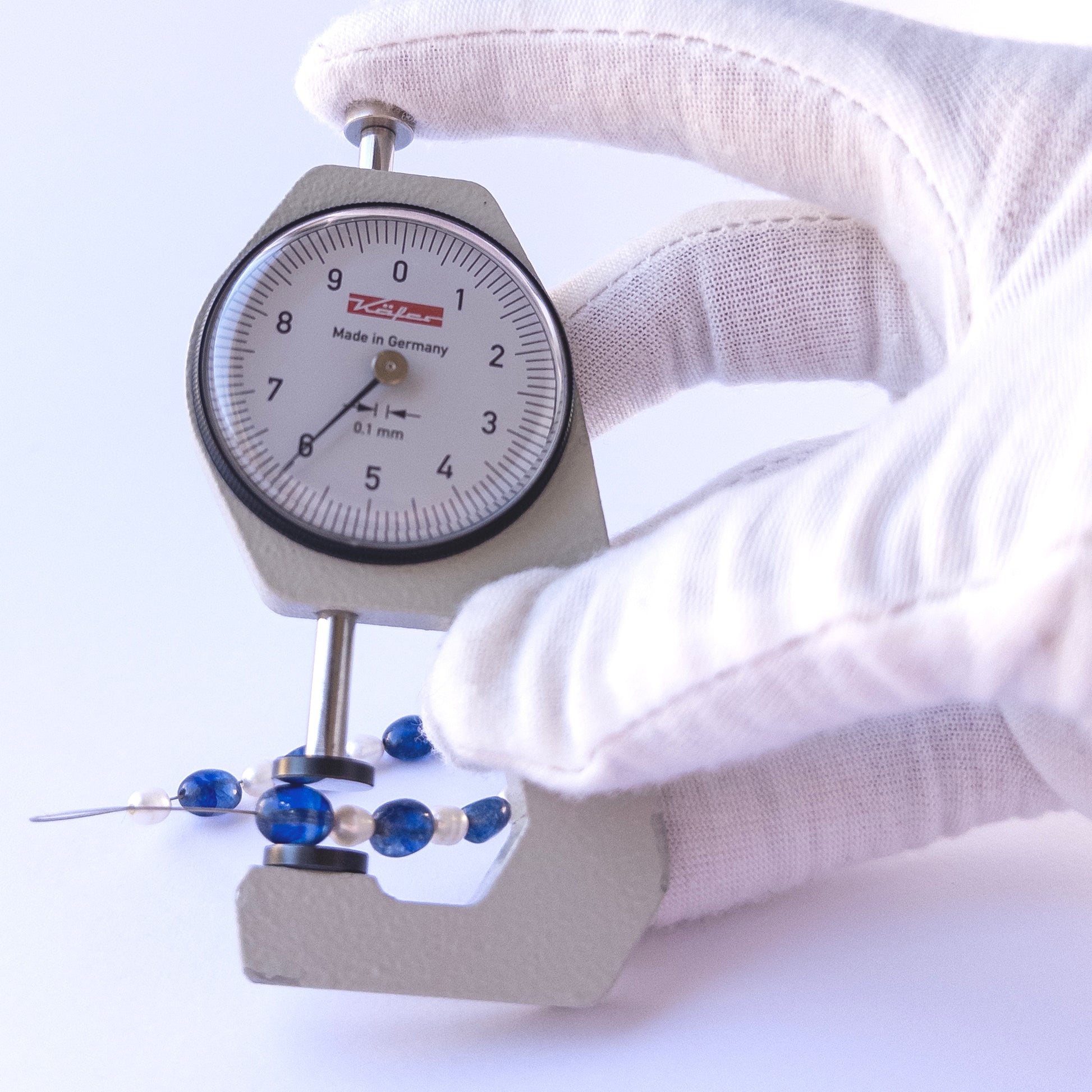 A dial gauge measures the Blue Sapphire & Freshwater Pearls Smooth Oval 6–7mm gemstone.