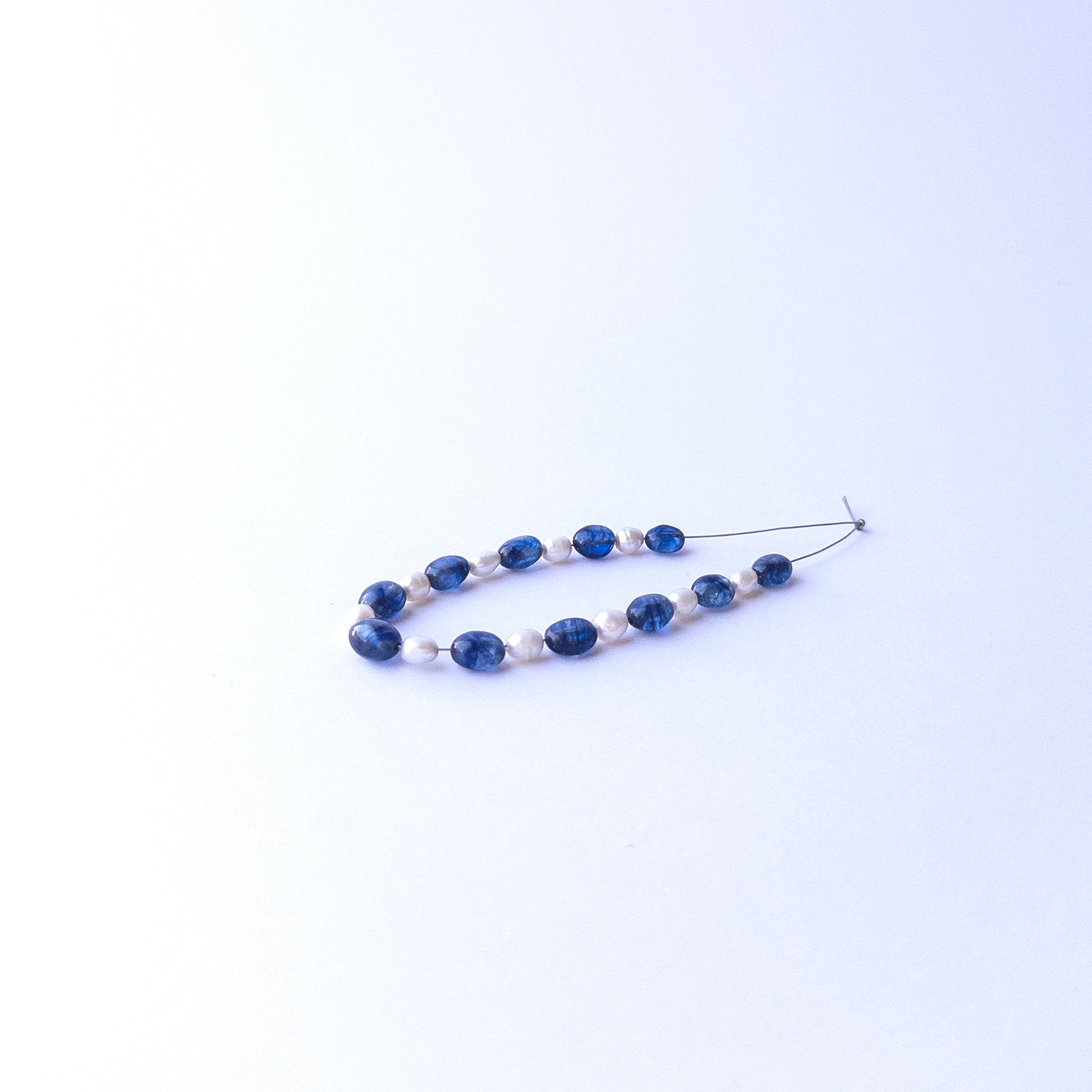 Blue sapphire and pearl smooth ovals arranged neatly, highlighting their polished surfaces for jewellery designers.