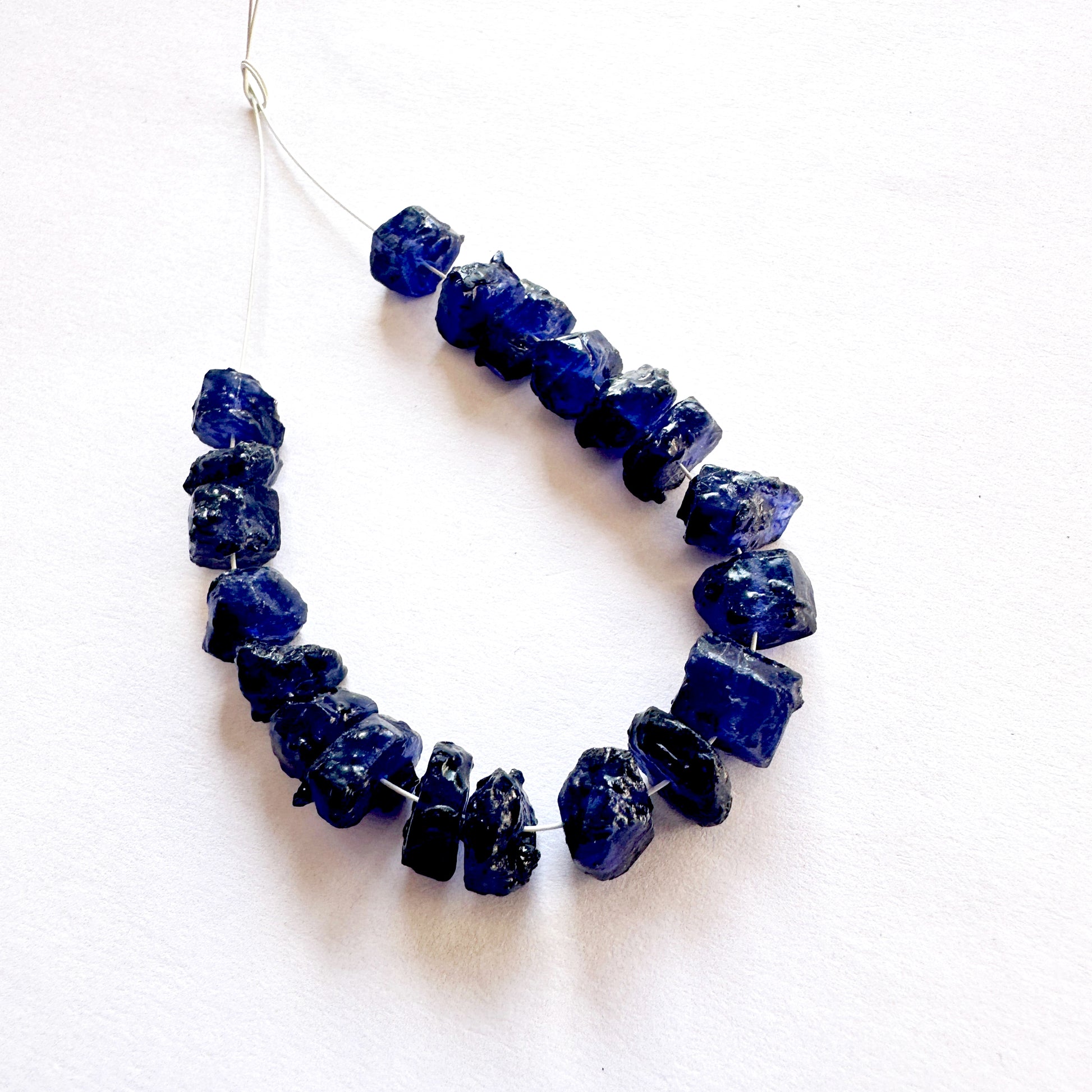 Close-up of rough Blue Sapphire beads with deep blue tones and natural texture.