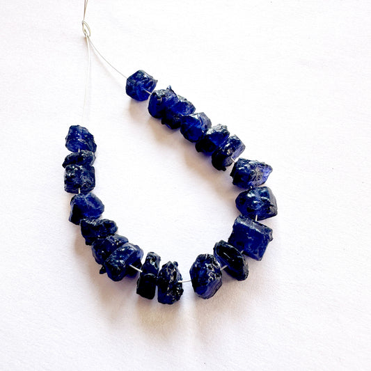 Close-up of rough Blue Sapphire beads with deep blue tones and natural texture.
