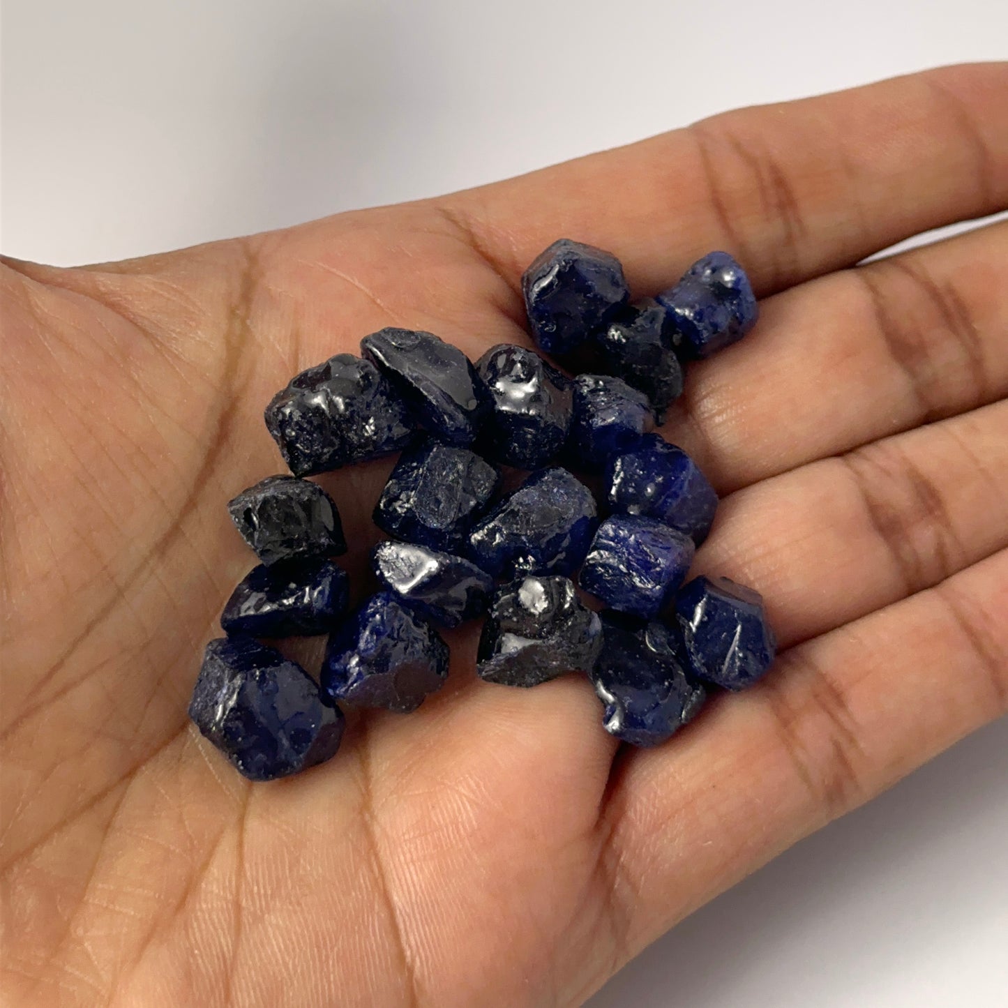 A person holds delicate pieces of Blue Sapphire rough, showcasing their natural rough design.