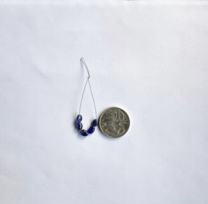 Blue Sapphire gemstone beads shine under soft lighting, enhancing their smooth oval cut and premium clarity.
