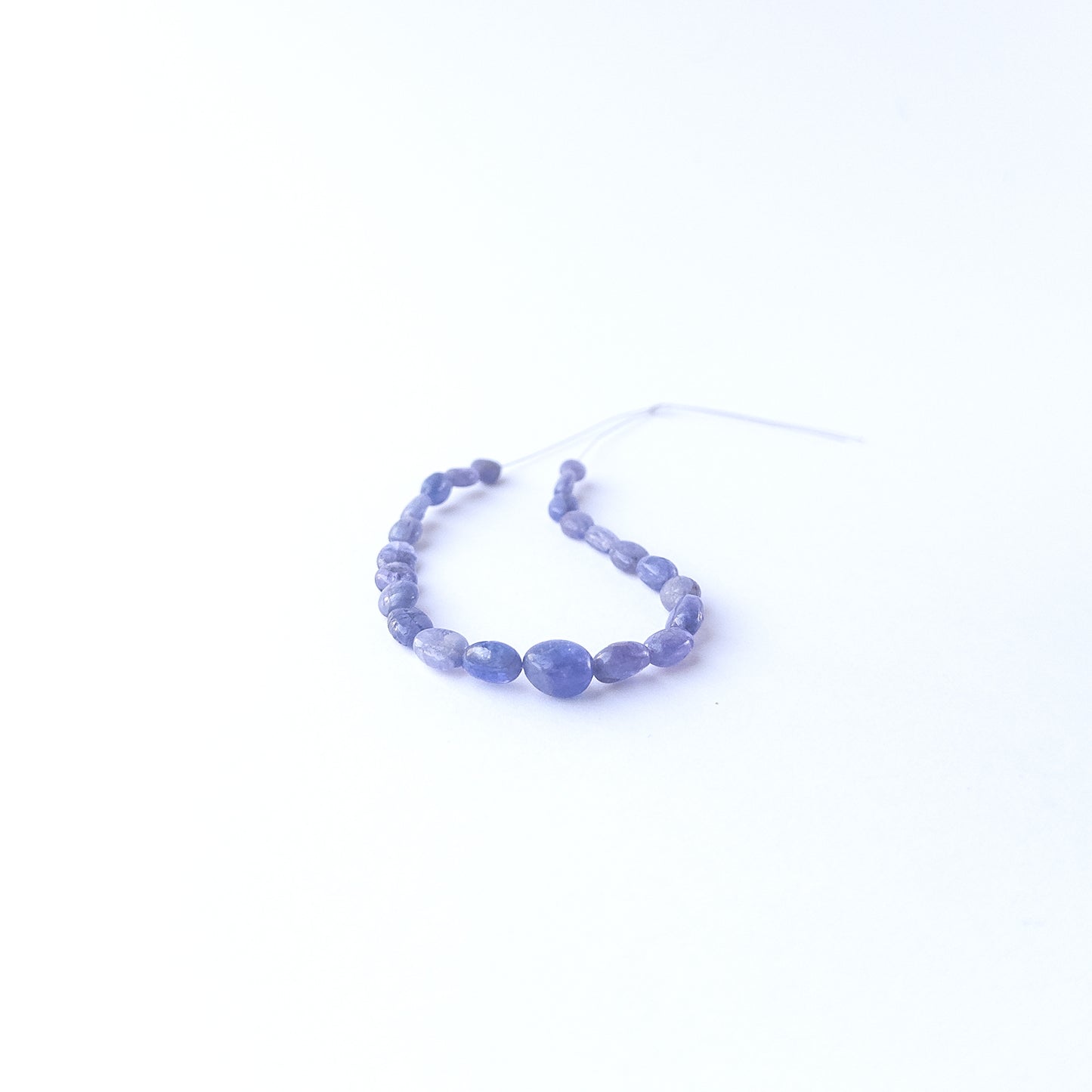 Handmade jewellery components featuring smooth Blue Sapphire oval beads in a neatly arranged set.