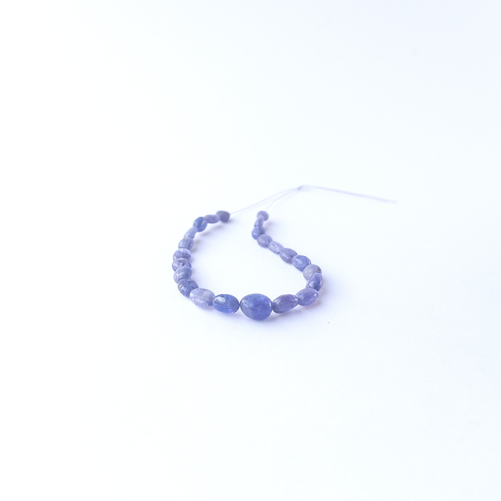 Handmade jewellery components featuring smooth Blue Sapphire oval beads in a neatly arranged set.