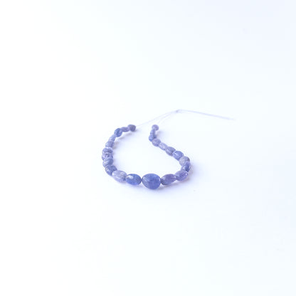 Handmade jewellery components featuring smooth Blue Sapphire oval beads in a neatly arranged set.
