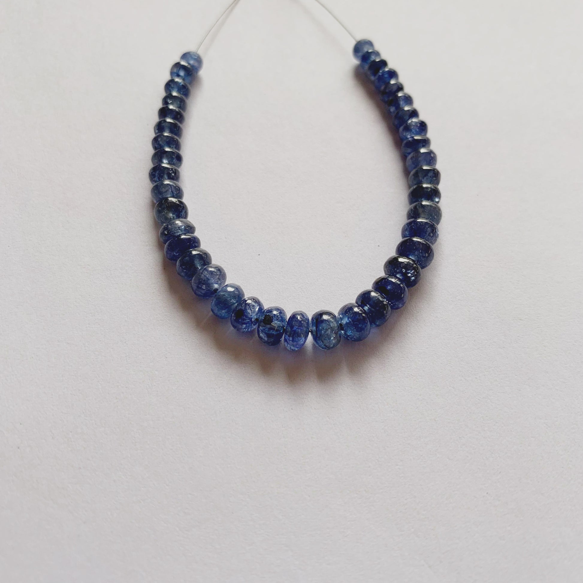 Natural Blue Sapphire beads in graduated sizes, highlighting their rounded cut and luminous blue hue.