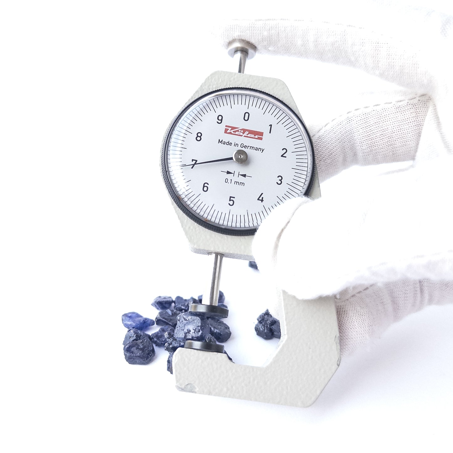 A dial gauge measures the Blue Sapphire rough 5.5–7mm gemstone.