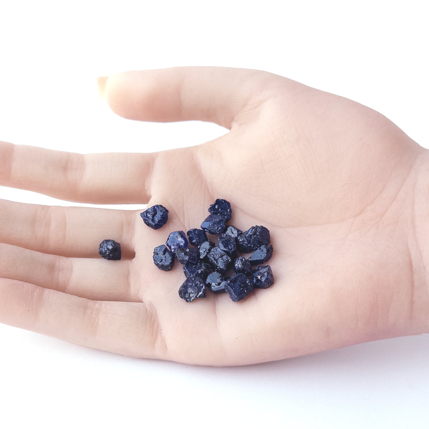 A person holds delicate pieces of Blue Sapphire rough, showcasing their natural design.