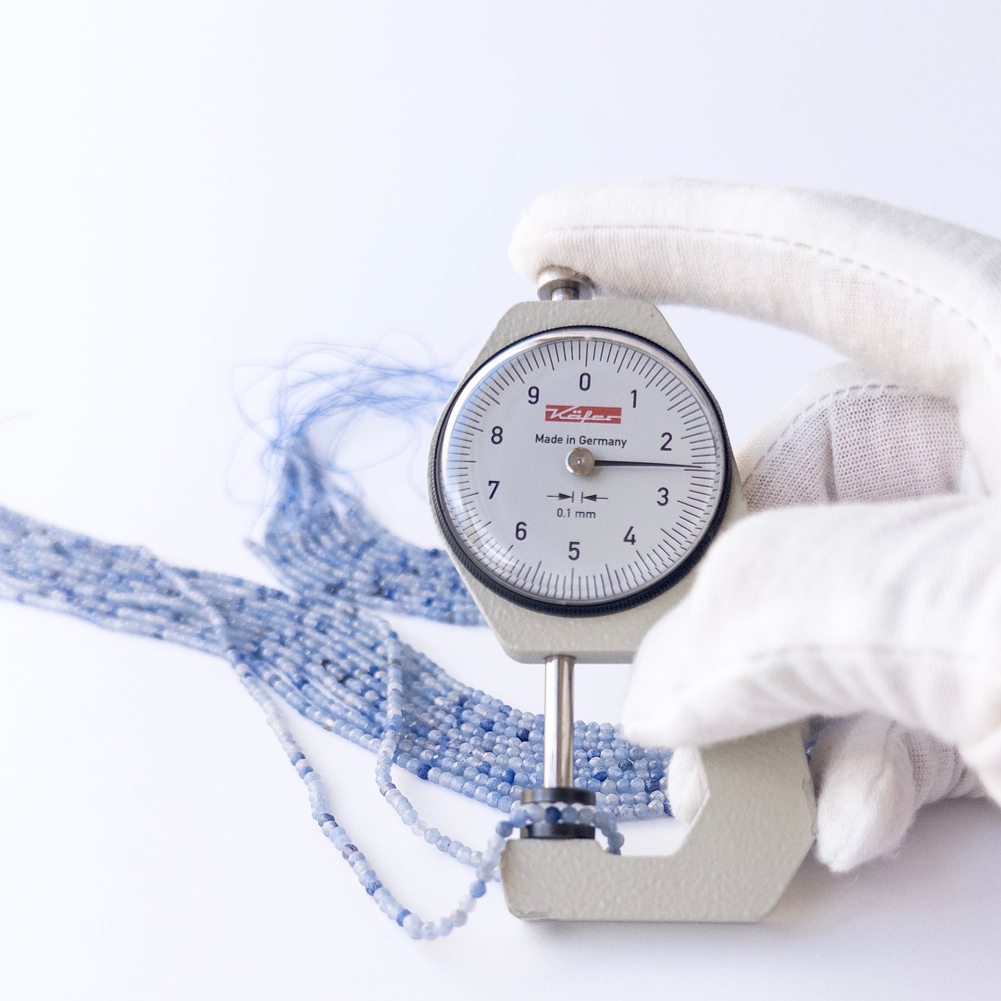A dial gauge measures the Blue Shaded Chalcedony faceted rondelle 2.5mm gemstone.