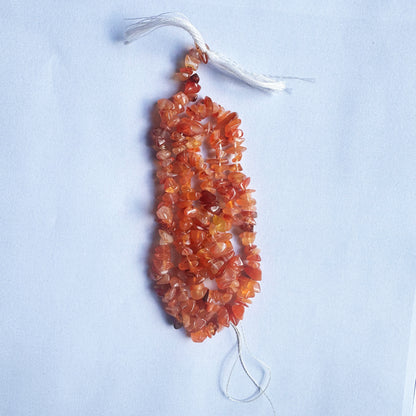 Close-up of Carnelian gemstone beads highlights their raw cut and rich, earthy hues.