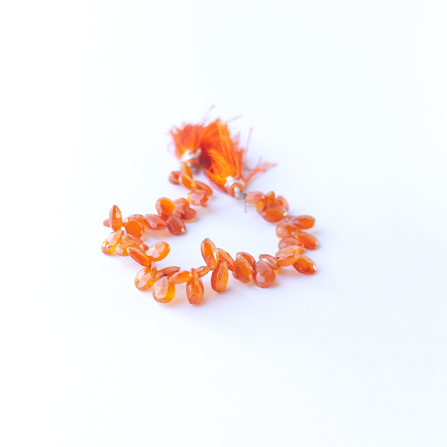 Carnelian briolette beads showcasing their glossy finish, colour variation and premium craftsmanship.
