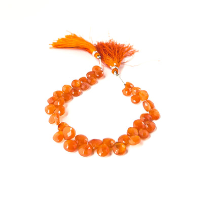 Carnelian faceted briolette beads sized 7.5–9mm arranged in a 20cm strand, showing warm orange tones and sparkling facets.