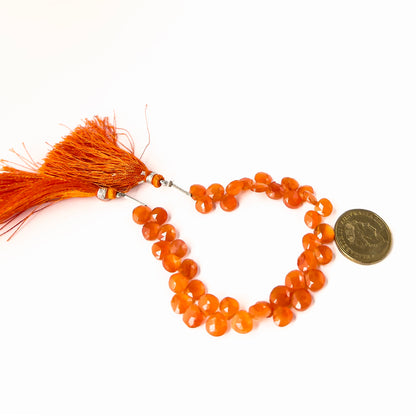 A coin is placed near Carnelian briolette beads to show the 7.5–9mm size range.