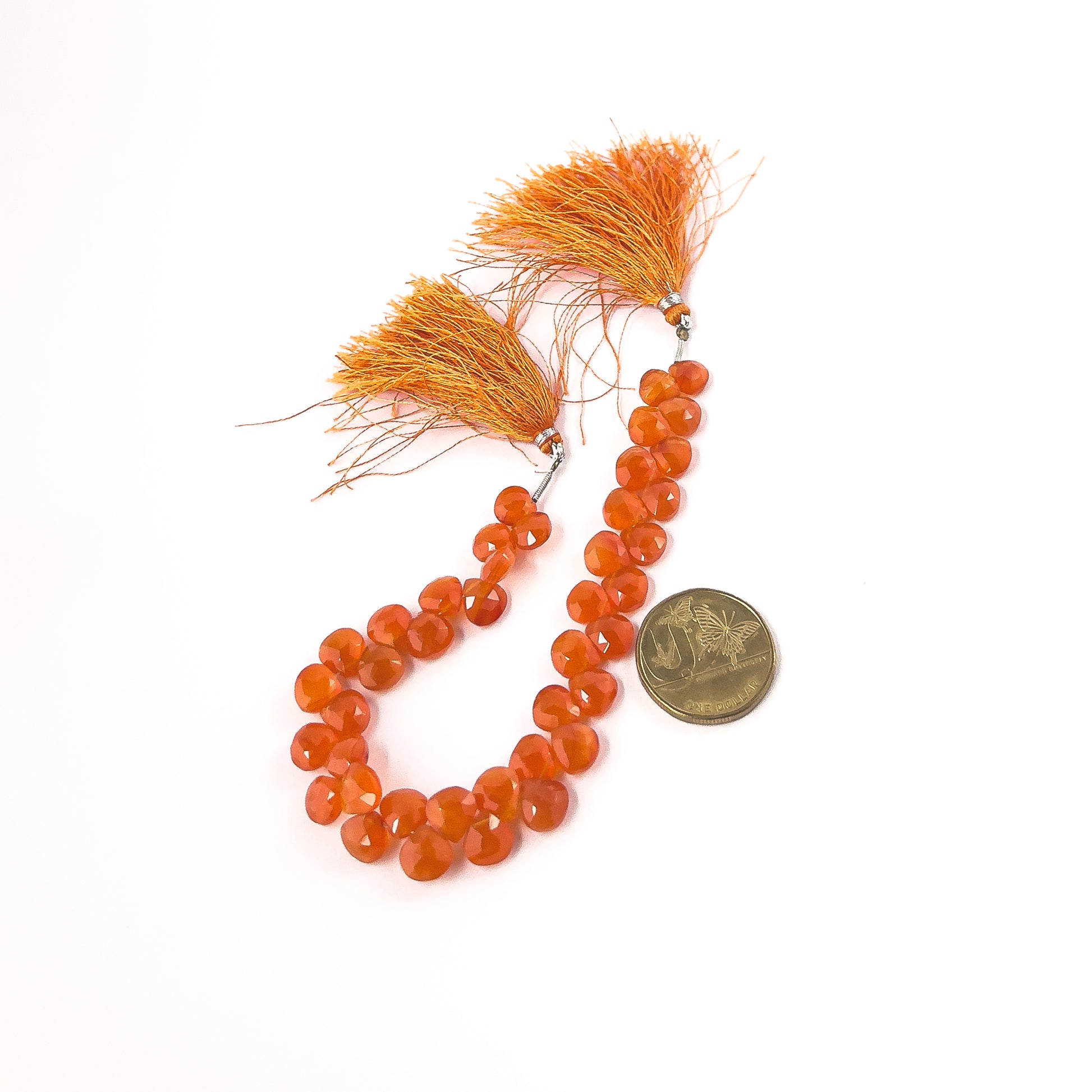 A coin is placed near delicate strands of Carnelian beads for scale.