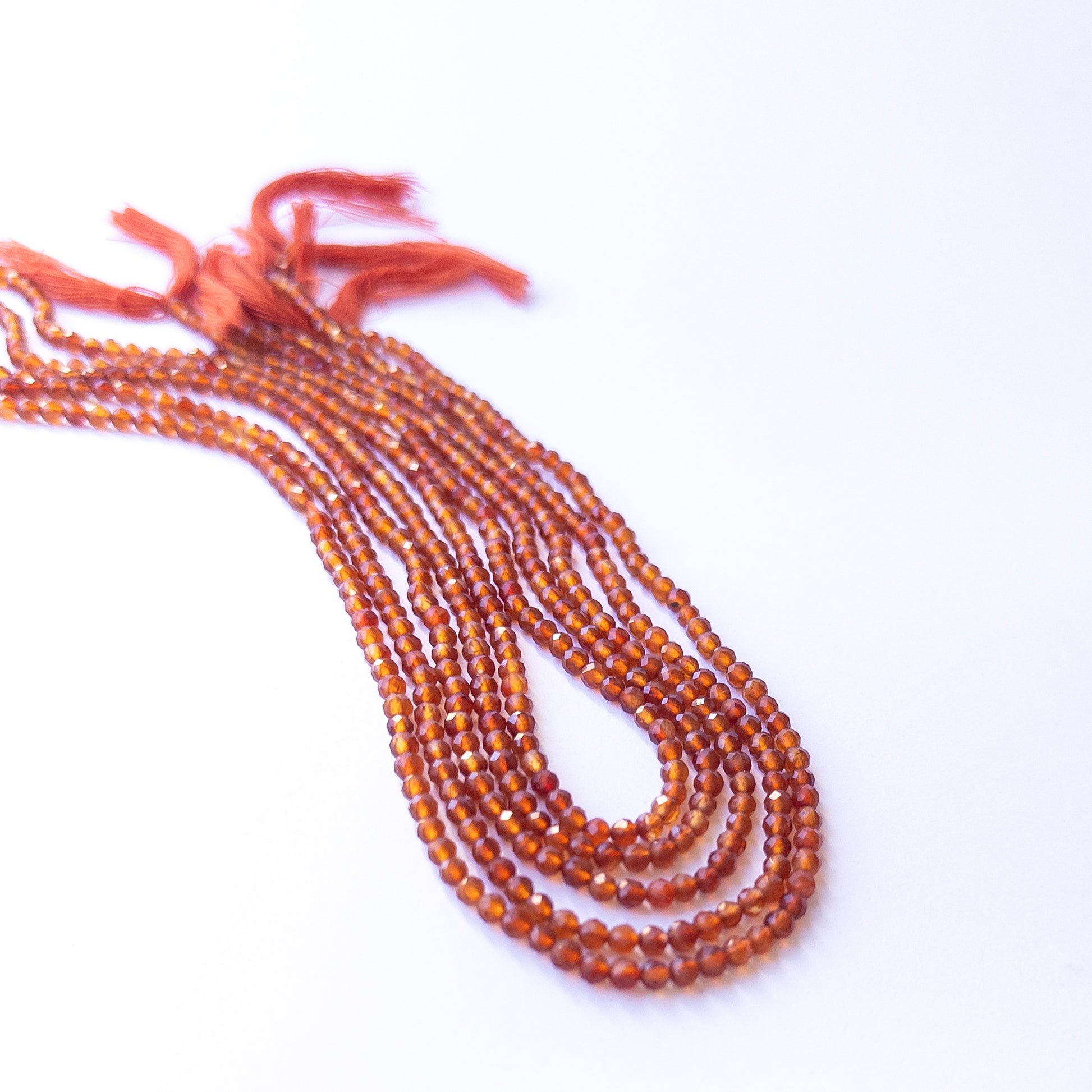 Premium Carnelian gemstone beads in faceted rondelle cut arranged in strands, showcasing warm fiery hues for jewellery designers.
