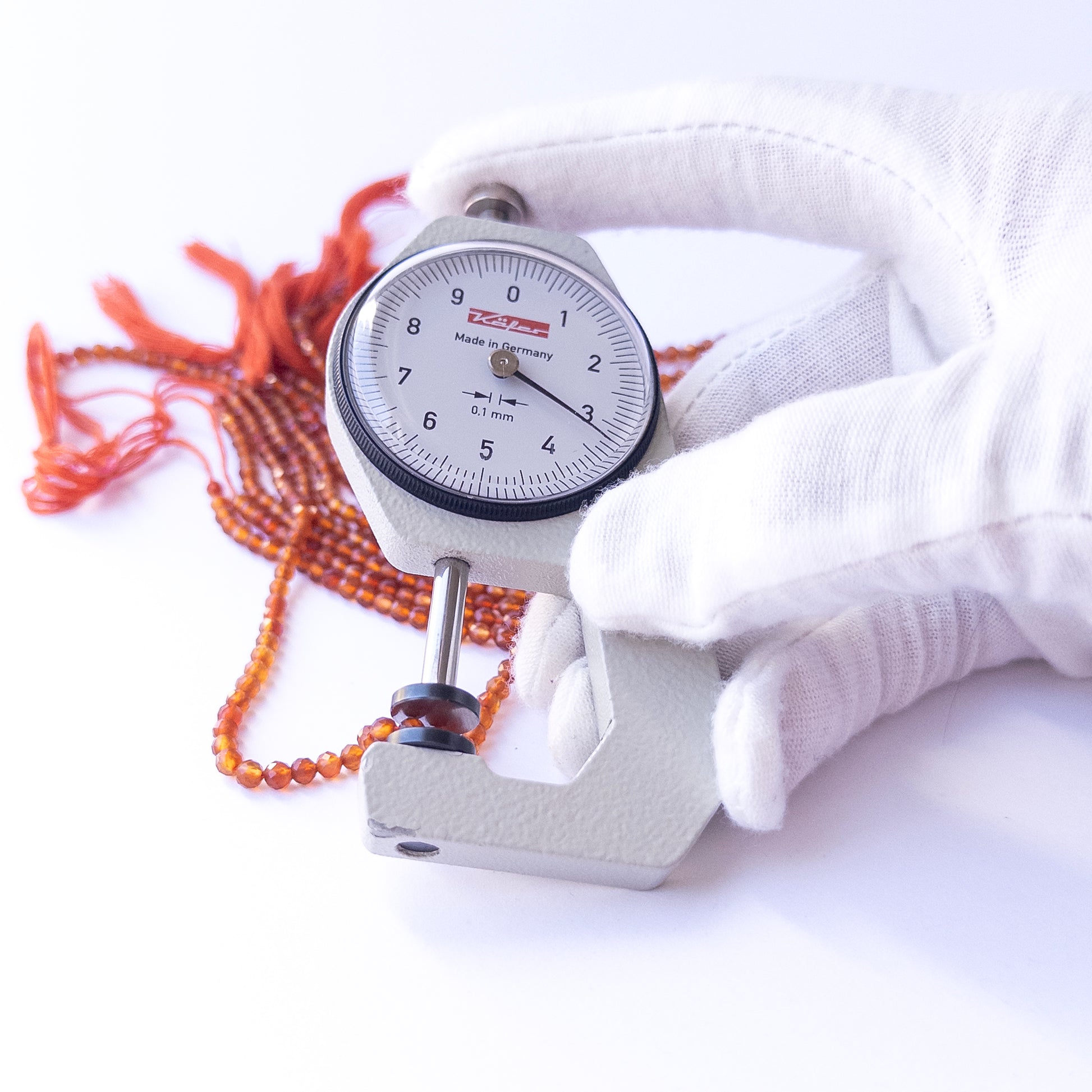 A dial gauge measures the Carnelian faceted rondelle 3.4mm gemstone.
