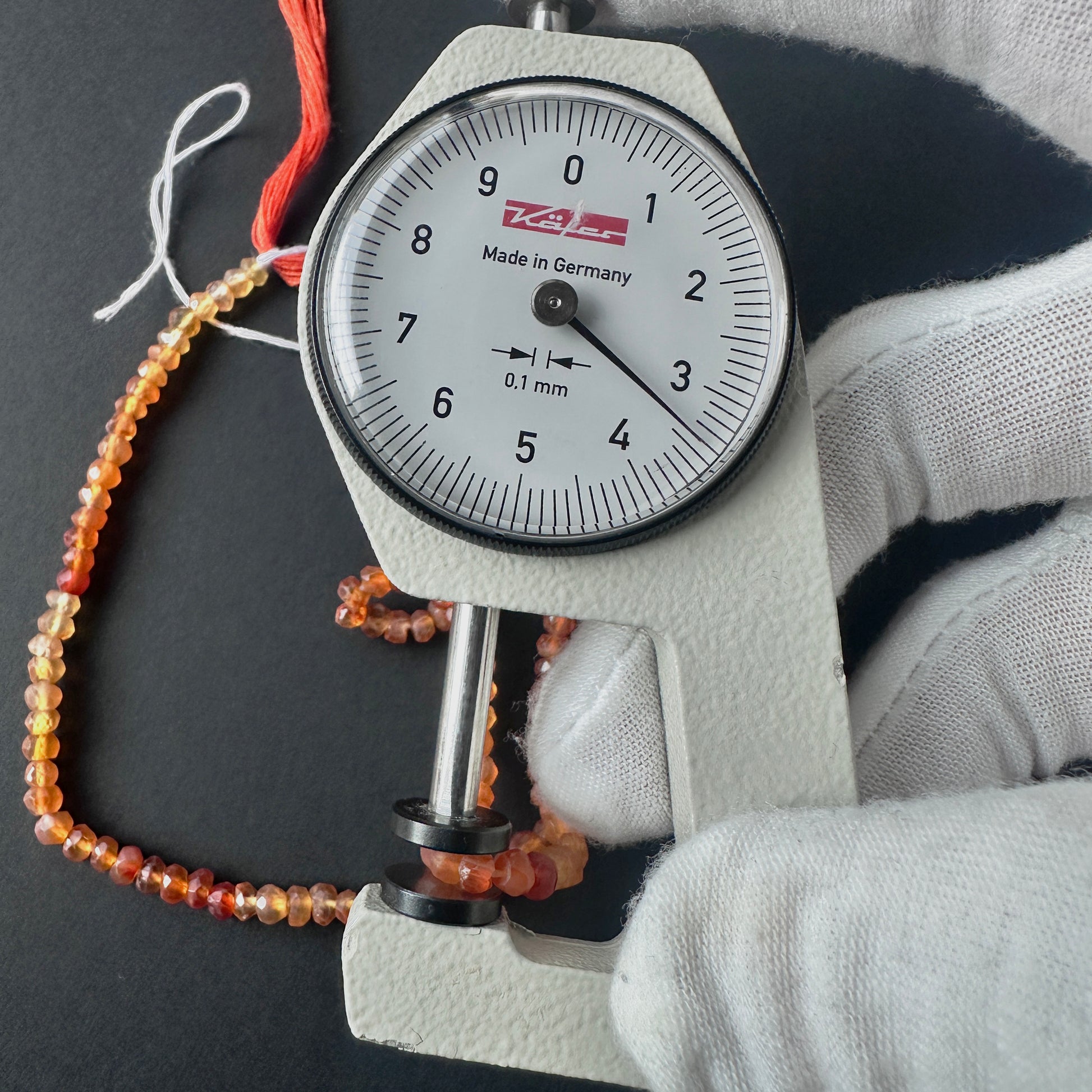 A dial gauge measures the Carnelian faceted rondelle 3.5mm gemstone.