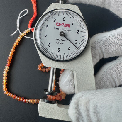 A dial gauge measures the Carnelian faceted rondelle 3.5mm gemstone.