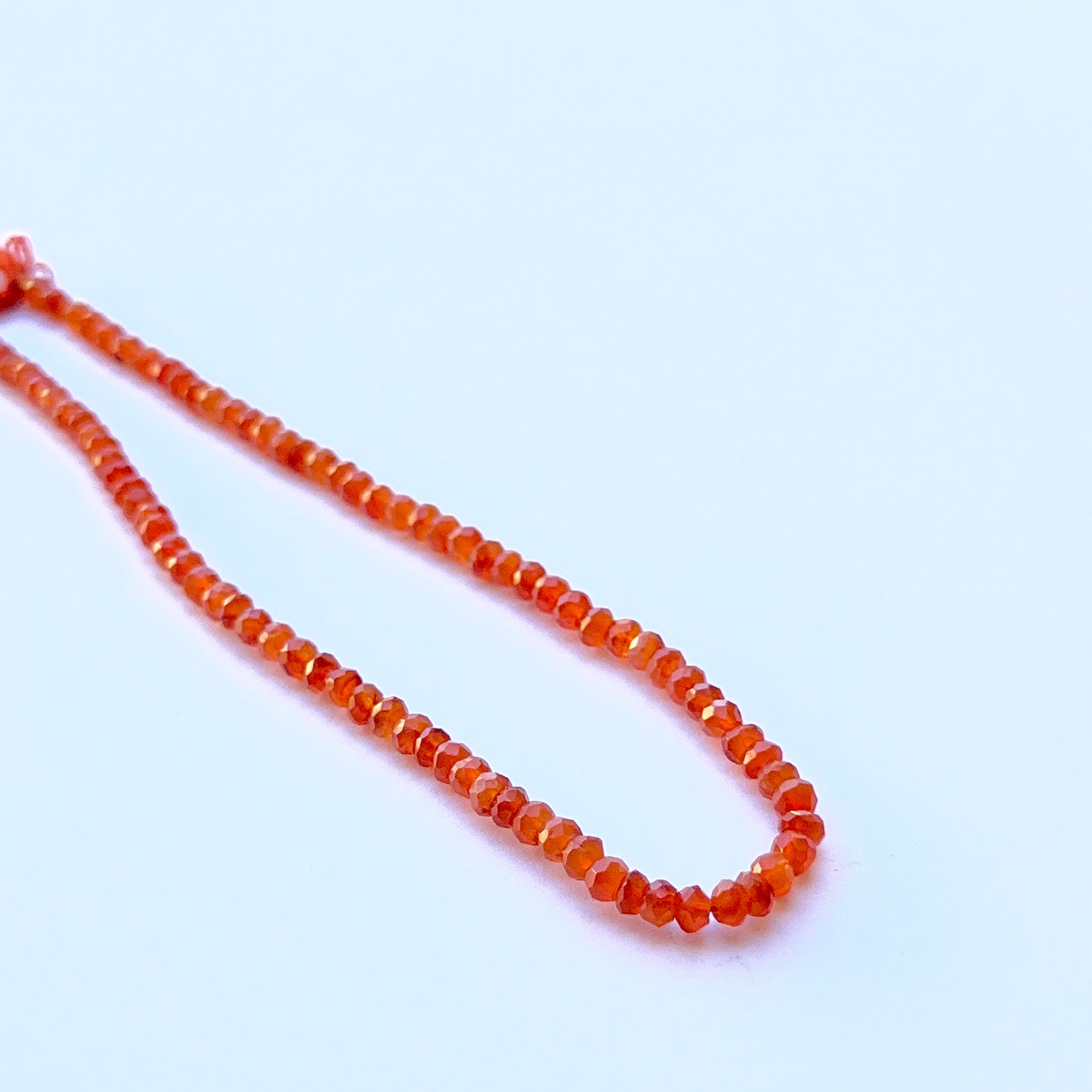 Carnelian faceted rondelle beads aligned on a strand highlighting clarity, shine and consistent sizing.