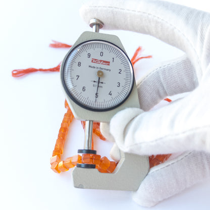 A dial gauge measures the Carnelian smooth cube 4.8–5.5mm gemstone.