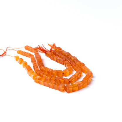 Carnelian smooth cube gemstone beads with warm orange tones arranged neatly for DIY jewellery making.