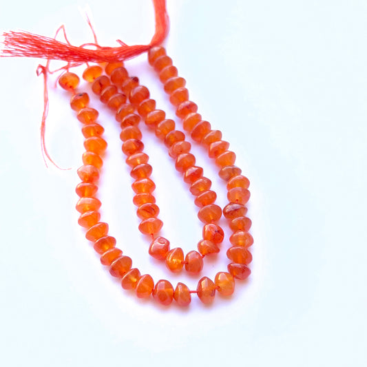 Carnelian smooth rondelle natural gemstone beads in warm orange tones arranged on a 14cm strand for handmade jewellery components.
