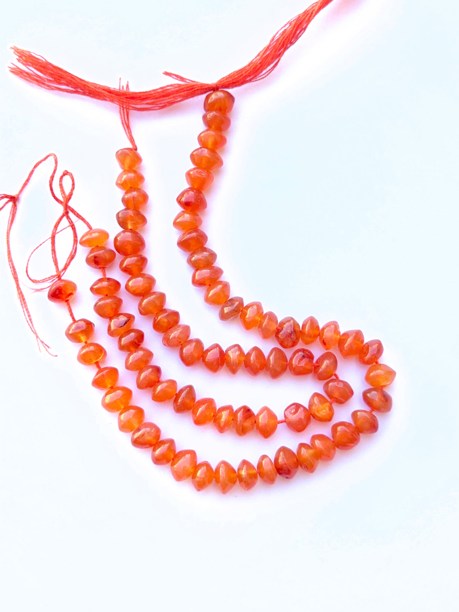 Carnelian smooth rondelle beads aligned on a strand highlighting clarity, shine and consistent sizing.