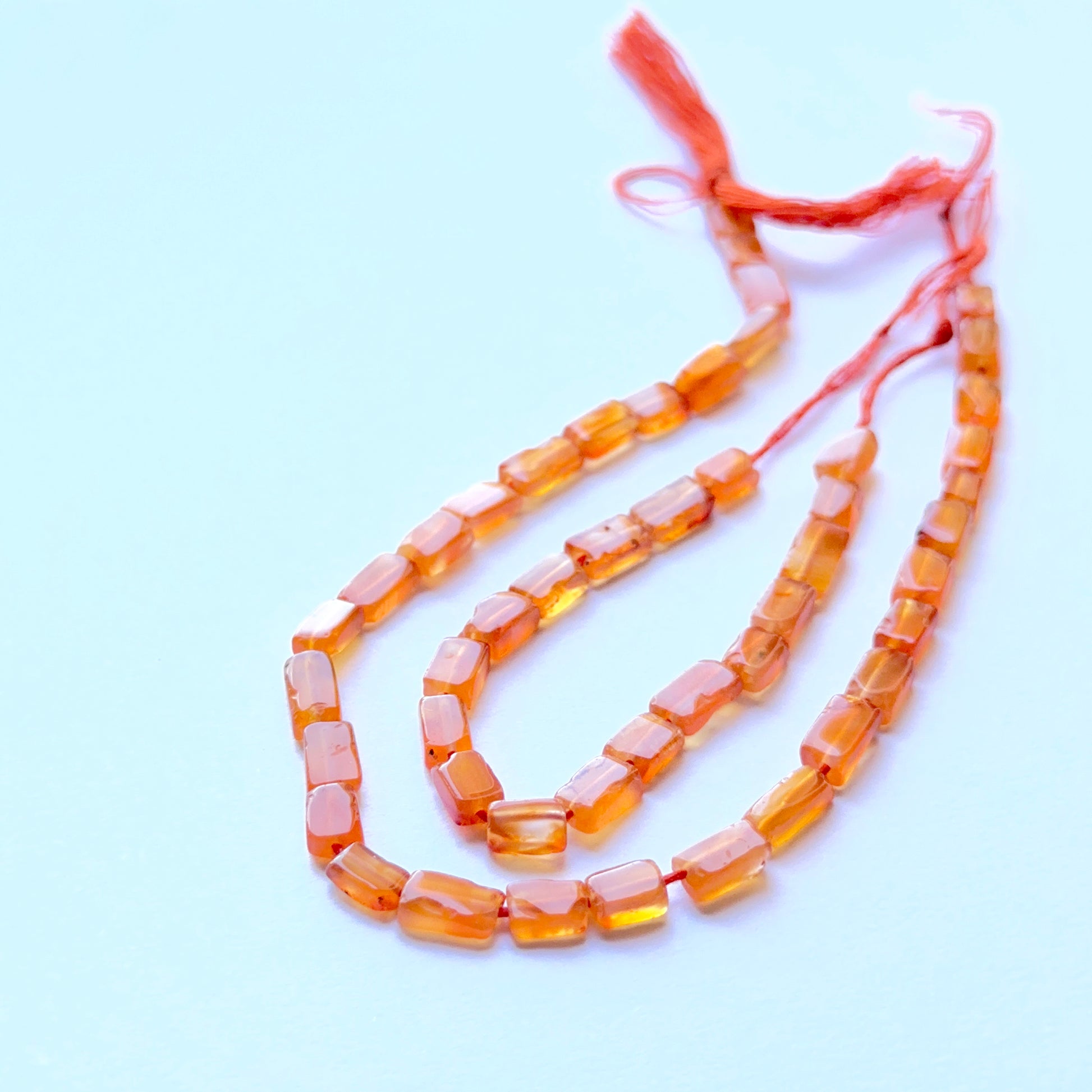 Carnelian smooth rectangle natural gemstone beads in warm orange tones arranged on a 21cm strand for handmade jewellery components.