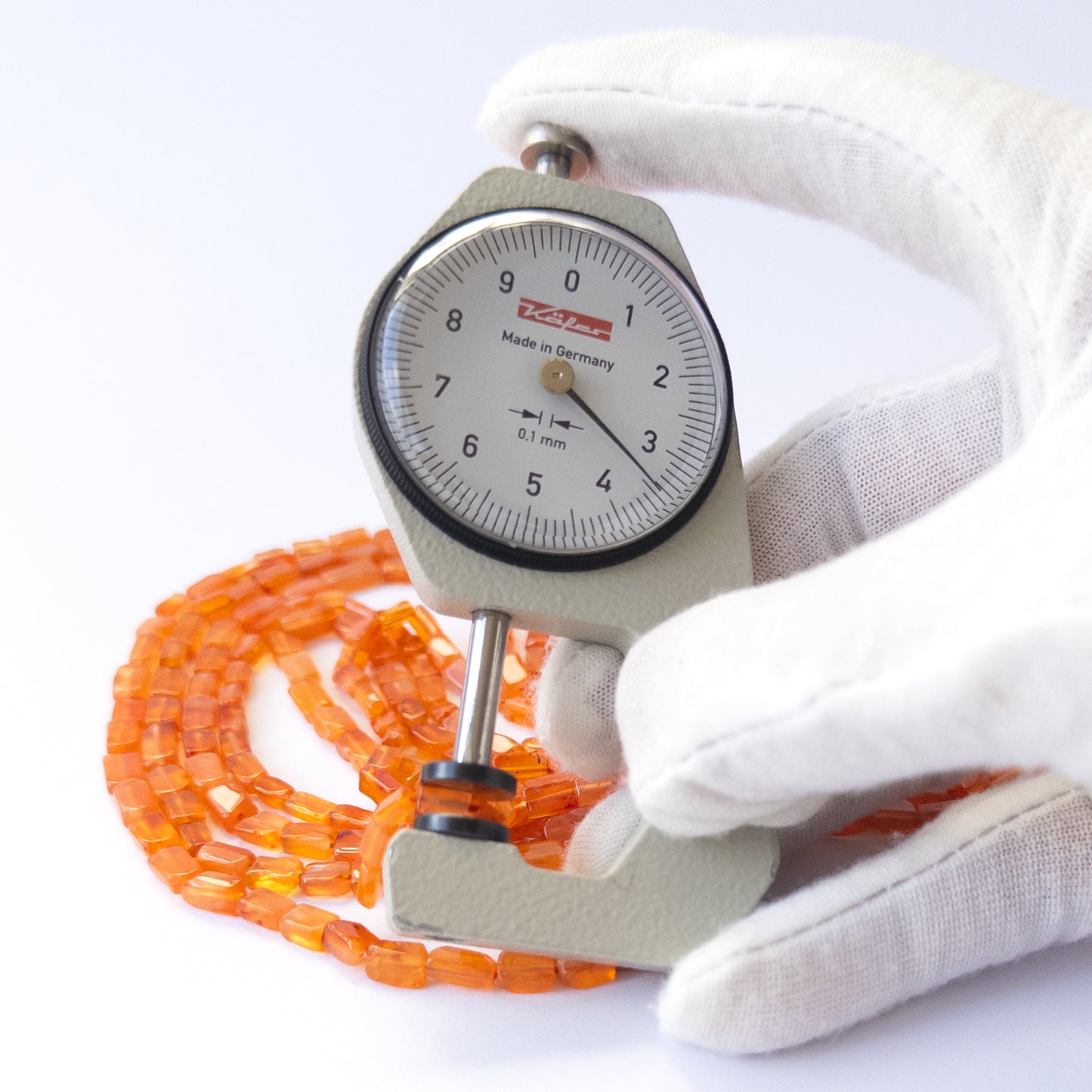A dial gauge measures the Carnelian smooth rectangle 3.5–4.5mm gemstone.