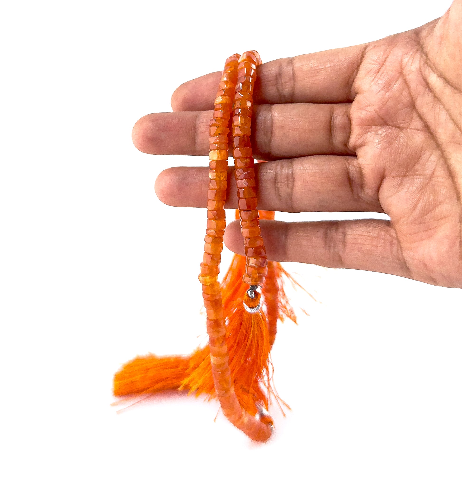 A person holds Carnelian smooth wheel beads, showing their rounded heishi design and warm colour palette.