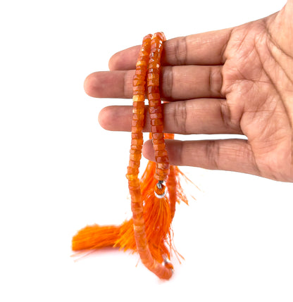 A person holds Carnelian smooth wheel beads, showing their rounded heishi design and warm colour palette.