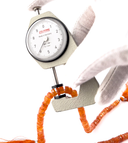 A dial gauge measures the Carnelian smooth wheel heishi 4.8–8.5mm gemstone.